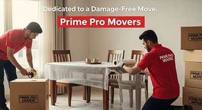 Movers packing a dining table and sealing household boxes inside a Punjab apartment